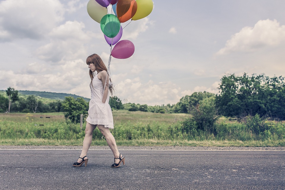 girl on white dress walking with balloons